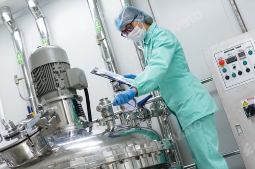 Preview: Scientist In Blue Lab Uniform Stand Near Big Pressure Tank , Hold Tablet , Look At Camera, Turned
