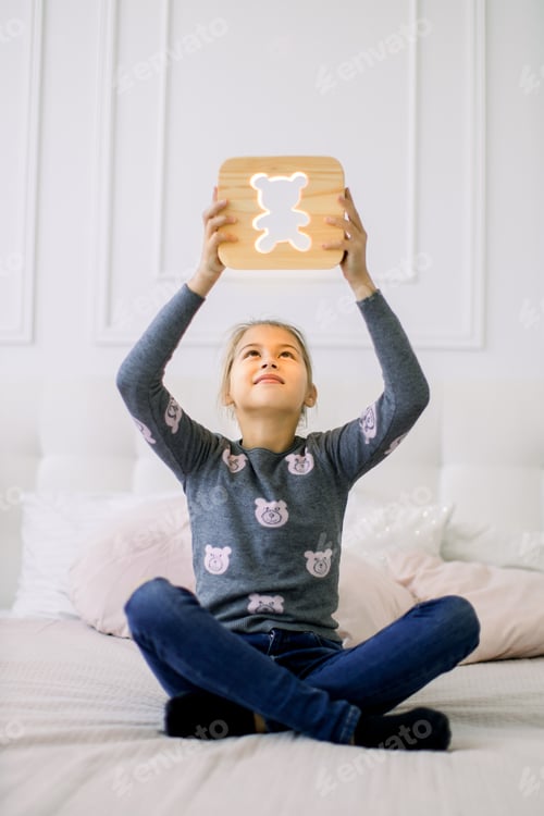 Preview: Indoor Portrait Of Pretty School Girl In Casual Domestic Wear, Sitting On The Bed In Lotus Position