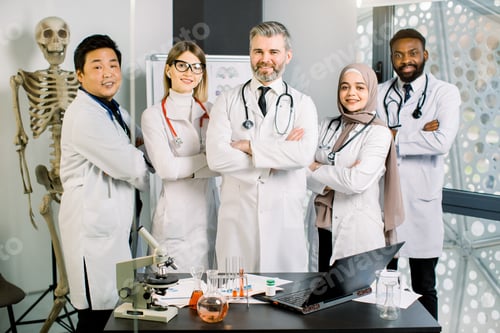 Preview: Smiling Multiethnic Group Of Doctors, Scientists In Modern Laboratory With Senior Male Leader. Team