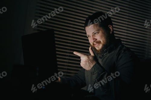 Visualização: Garoto sorridente falando por videochamada com a namorada usando o laptop à noite e mostrando o indicador