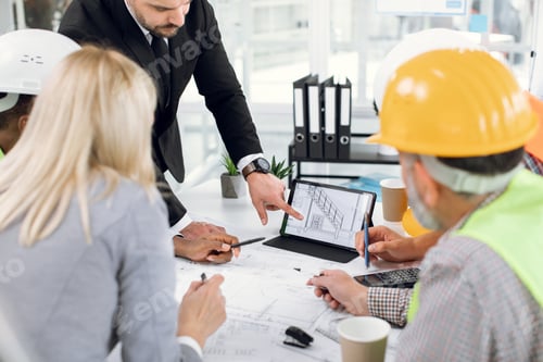 Preview: Close Up Of Construction Team Analysing Blueprints During Business Meeting At Office. Multiracial