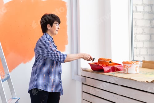 Preview: Happy Smiling Middle-Aged Woman Painting Interior Wall Of New House. Redecoration, Renovation