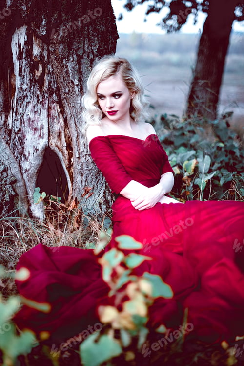 Preview: Fashion Gorgeous Young Blonde Woman In Beautiful Red Dress In A Fairy-Tale Forest. Magic Atmosphere