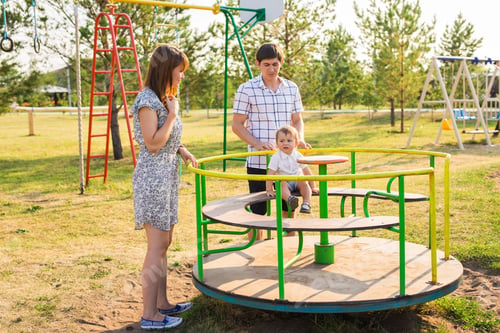 Preview: Playful Child With Parents At The Playground Outdoor. Mom, Dad And Child.