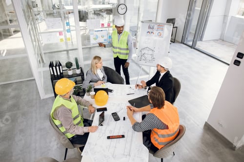 Preview: Top View Of Five Multiracial Colleagues In Formal Wear And Helmets Having Working Conference At
