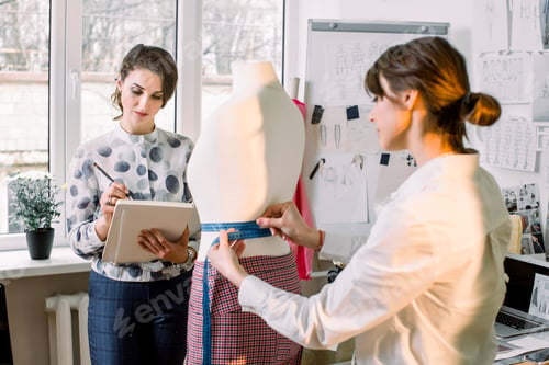 Preview: Back View Of Female Dressmaker Measuring Mannequin With Tape In Atelier Office. Talented Fashion