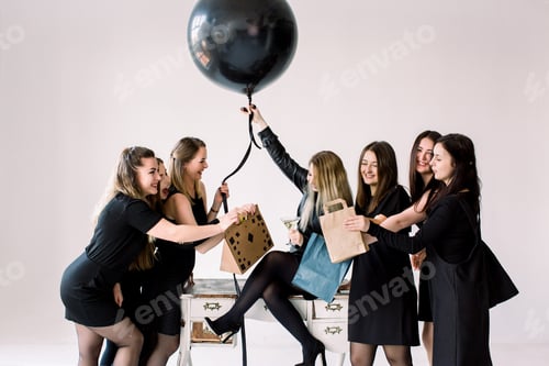 Preview: Pretty Girl Sitting On The Vintage Table And Holding Big Black Balloon. Her Beautiful Six Friends
