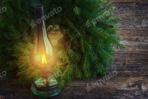 Preview: Vintage Glowing Lantern With Evergreen Wreath On Wooden Table, Low Key