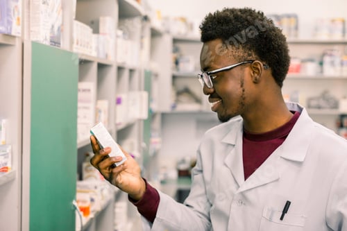 Preview: Close-Up Portrait Of Young African American Man Pharmacist Searching Prescribed Drug On Shelves In