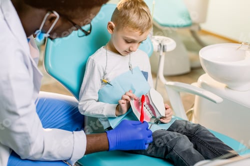 Preview: Little Caucasian Boy Is Sitting In Dental Chair And Smiling To African American Dentist With