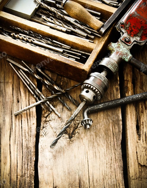 Preview: The Old Working Tool. An Old Drill, A Box With Drills On A Wooden Background.