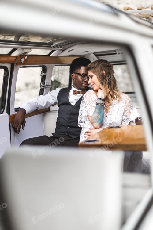 Preview: Merry Happy Young Multiracial Couple Hugging Sitting In A Retro Bus