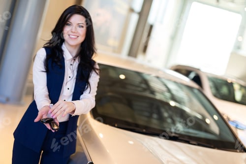 Preview: Happy Woman Buyer Possing With Keys Near Her New Vehicle In Car Dealership