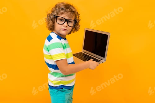 Preview: Curly Red-Haired Boy With Glasses In A Striped T-Shirt Holding A Laptop In His Hands On A Yellow