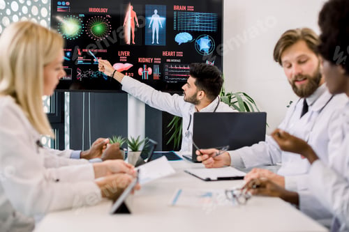 Preview: Young Indian Doctor Advises His Multiethnical Colleagues During A Medical Meeting, Pointing On Big