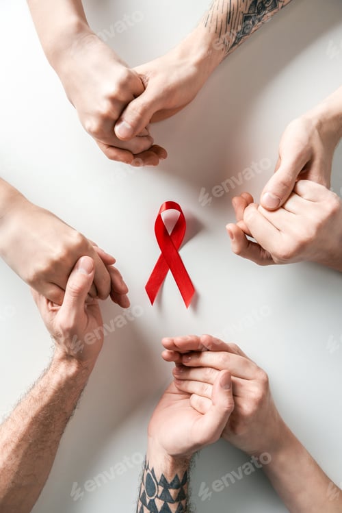 Preview: top view of people holding hands and aids awareness red ribbon on white background