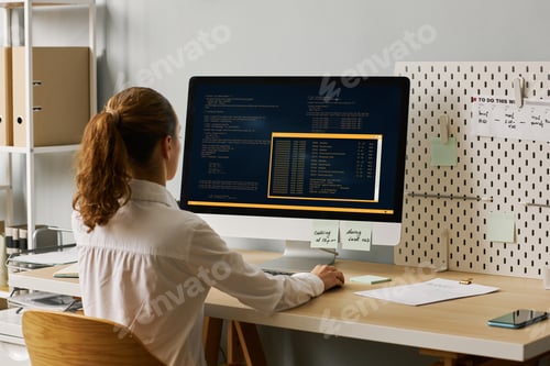 Preview: Back view female programmer writing code working at desk