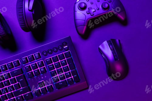 Preview: Top view of illuminated gaming gadgets on purple desk