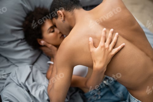 Preview: top view of passionate african american woman making love with shirtless man at home
