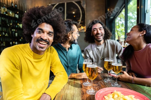 Preview: Group of happy young adult friends toasting beer at happy hours after work