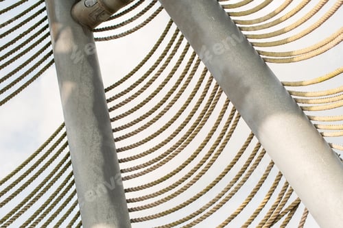 Preview: several rows of braided ropes diagonally against green foliage of trees, textured background