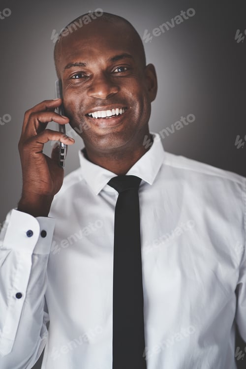 Preview: African businessman talking on his cellphone against a gray background