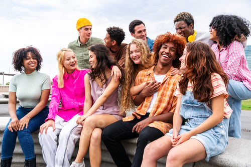 Preview: Happy playful multiethnic group of young friends bonding outdoors
