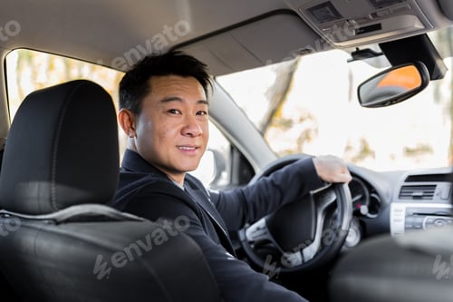 Vista previa: A man driving an Asian car behind the wheel looks at the camera and smiles