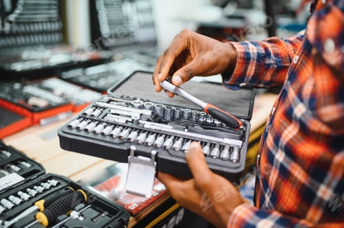 Preview: African american male buyer chooses a toolbox in a hardware store. A large selection of tools