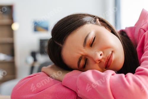 Preview: Young girl, teenager feeling sad sleeping on folded arms at home