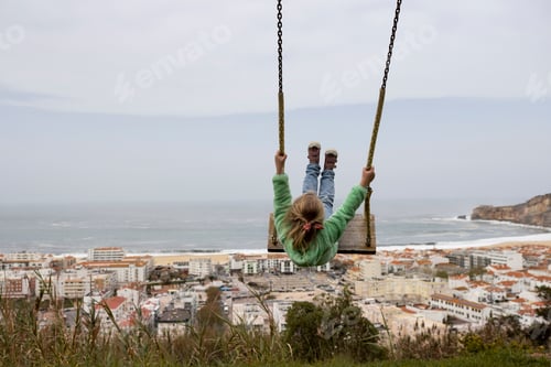 Preview: Little girl swinging against the scene of Nazare coast in Portugal