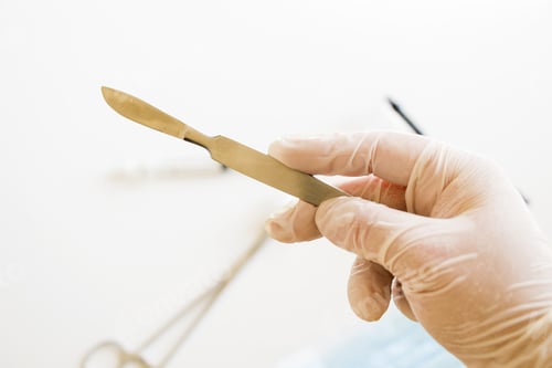 Preview: Closeup shot of a gloved hand holding a surgical scalpel