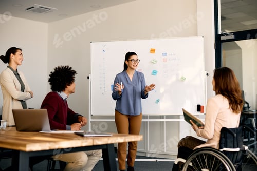 Preview: Young happy businesswoman giving presentation to group of her colleagues in meeting room.