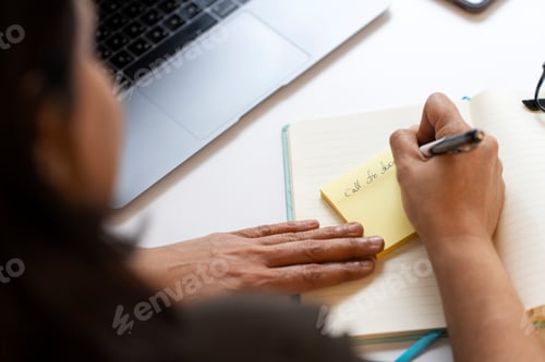 Preview: Woman hand taking notes, writing text on sticky note, planning project, selective focus