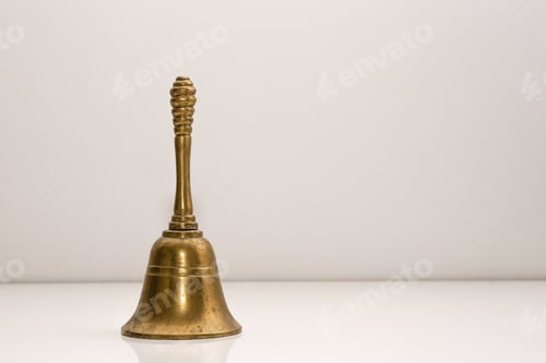 Preview: Closeup shot of a golden handbell on a white wall background