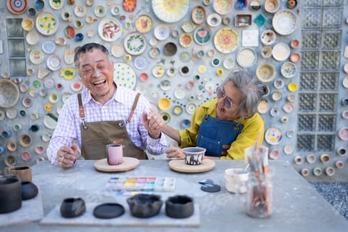 Preview: Asian retired couple is engaged in pottery making and clay painting activities.