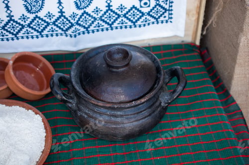 Preview: Black clay pot with a lid with flour in the clay plate near it