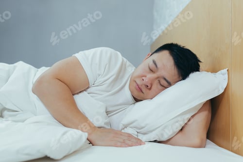 Preview: Sad Asian lying in a bed under a blanket, a depressed man in the morning