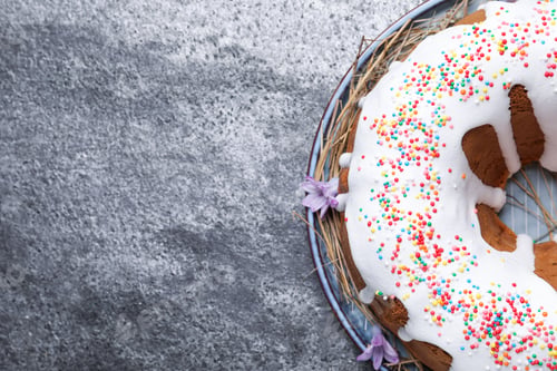 Preview: Glazed Easter cake with sprinkles on grey table, top view. Space for text