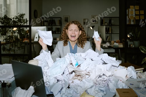 Preview: Stressed Young Woman Sitting at Desk Handling Paperwork