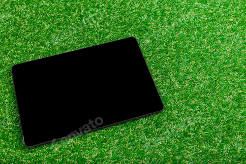 Preview: Tablet resting on artificial grass during a sunny day, showcasing a vibrant green landscape and
