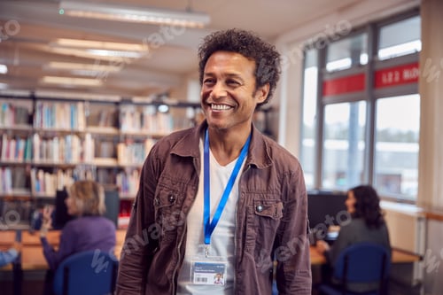 Preview: Portrait Of Mature Male Teacher Or Student In Library With Other Students Studying In Background