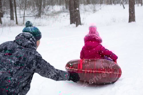 Visualização: Papai monta sua filha em um tubo de um escorregador no inverno em uma nevasca