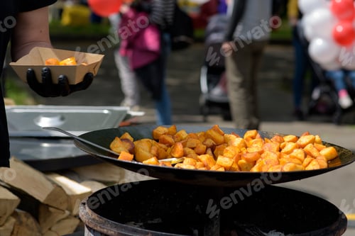 Preview: Chunks of fried potatoes in a large skillet during the street food festival.