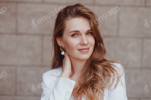 Vista previa: Mujer de negocios con traje blanco posando al aire libre.