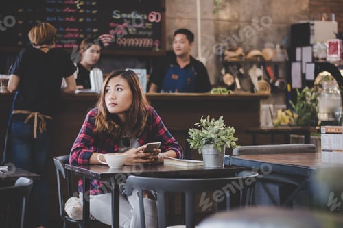 Preview: Portrait of young hipster woman use mobile phone while sitting in table coffee shop.
