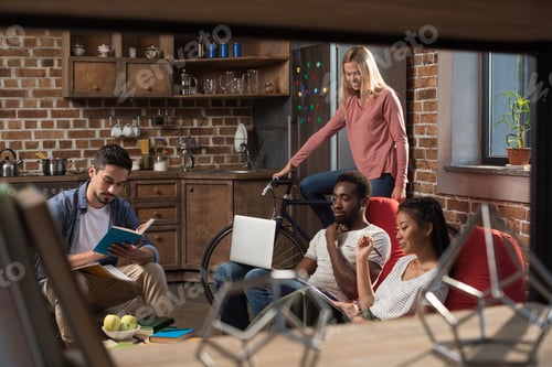 Preview: multiethnic students with laptop and books studying while girl riding bicycle