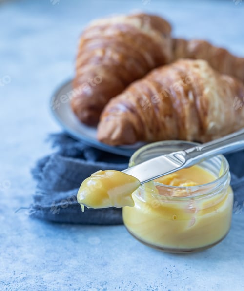 Preview: French croissant. Freshly baked croissants with honey on blue concrete background.