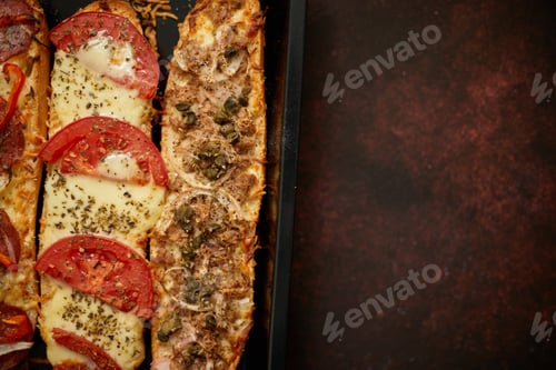 Preview: Long baguettes pizza sandwiches with tuna, mushrooms, tomatoes and cheese on a metal baking tray