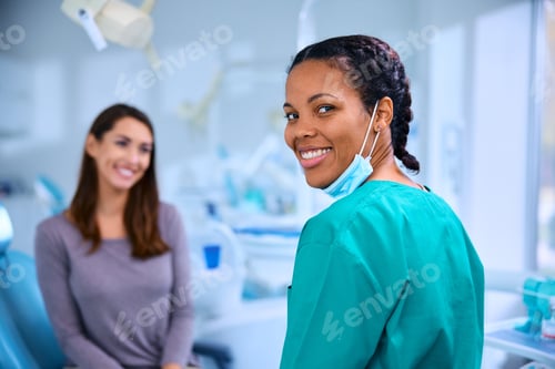 Preview: Happy black female dentist at work looking at camera.